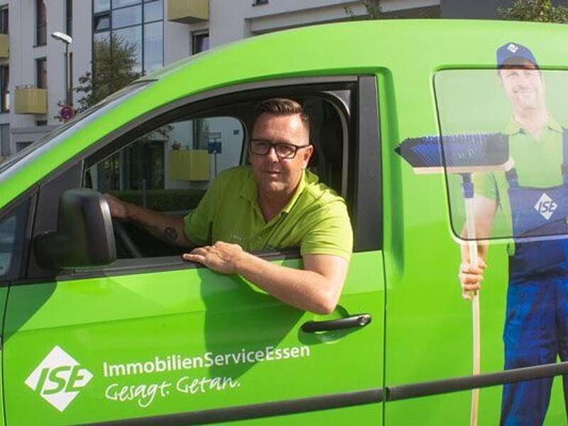 Mitarbeiter in grünem Auto, guckt auf Fenster